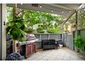 Cozy outdoor patio with grill, storage bench, diamond-patterned rug, and mature landscaping at 2773 S Lansing Way, Aurora, CO 80014