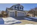 Two-story house, gray siding, three-car garage, snowy yard at 16424 E 107Th Pl, Commerce City, CO 80022