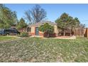 A brick home with green grass and trees in the front yard at 2220 Quebec St, Denver, CO 80207