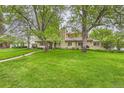 Lush front lawn with mature trees leading up to the inviting home facade at 2 Elm St, Denver, CO 80220