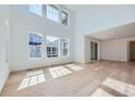 Bright living room with soaring ceilings, large windows, and light wood floors at 4652 Windmill Dr, Brighton, CO 80601