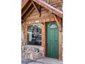 Inviting entrance featuring a green front door, large window, stone accents, and a charming address plate at 26288 S End Rd, Kittredge, CO 80457