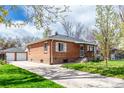 Brick home featuring an extended driveway leading to a detached garage and a landscaped lawn at 4433 S Washington St, Englewood, CO 80113