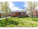 Traditional brick home featuring a welcoming front yard and a classic design with white shutters, creating an inviting atmosphere at 4433 S Washington St, Englewood, CO 80113