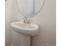 Close-up view of a stylish powder room sink and mirror, complemented by elegant fixtures and neutral walls at 45952 Gentry Ave, Bennett, CO 80102