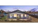 Charming gray home with a cozy, fenced front yard and inviting curb appeal at dusk at 13619 Lake Ave, Brighton, CO 80603