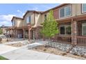 Attractive townhome featuring a stone facade, covered porch, and low maintenance landscaping with neutral color palettes at 11228 Bella Vita Dr, Broomfield, CO 80020