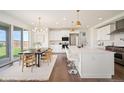 Bright, modern kitchen with stainless steel appliances, white cabinetry, large island and adjacent dining area at 14391 Shasta Daisy Pt, Parker, CO 80134