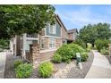 Exterior of the property showcasing stone accents, landscaping, and ample greenery at 13275 Holly St # B, Thornton, CO 80241