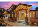 Inviting front entry featuring a beautiful wood door and natural stone accents under timber framing at 6016 Stone Creek Dr, Evergreen, CO 80439