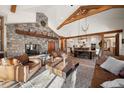 Spacious living room featuring stone fireplace, wood beams, and open floor plan to the kitchen at 6016 Stone Creek Dr, Evergreen, CO 80439