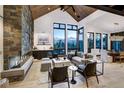 Spacious living room featuring a stone fireplace, vaulted ceilings, and expansive windows showcasing mountain vistas at 2300 Boreas Pass Rd, Breckenridge, CO 80424