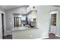 Well-lit kitchen boasts white cabinets, stainless steel appliances, and a convenient breakfast bar for casual dining at 4760 S Wadsworth Blvd # 205, Littleton, CO 80123