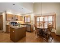 Open kitchen featuring wooden cabinetry, an island, stainless appliances, and an adjacent breakfast nook at 6073 W Adriatic Pl, Lakewood, CO 80227