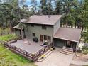 Aerial view displays backyard wooden deck, brick patio, and lush landscaping, enhancing outdoor living at 4515 Red Rock Dr, Larkspur, CO 80118