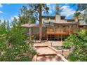 View of backyard landscaping with stone walkway leading to a wooden deck, blending with the natural surroundings at 4515 Red Rock Dr, Larkspur, CO 80118