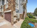 A ground level garage with stone accents and a side entrance to the upper-level floors of a condo at 9363 Amison Cir # 106, Parker, CO 80134