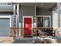 Inviting front porch with brick accents, a red door, white columns, and a cozy bench, creating a welcoming entrance at 4947 Stoneham Ave, Castle Rock, CO 80104
