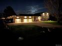 Charming home featuring a well-lit driveway and garage, complemented by a landscaped yard at night at 8700 S Ammons St, Littleton, CO 80128