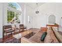 Bright living room with large arched window, hardwood floors, and leather furniture at 10115 Cook St, Thornton, CO 80229