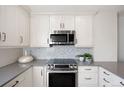 Updated kitchen featuring stainless steel appliances, white cabinetry, and modern backsplash at 480 S Marion Pkwy # 306, Denver, CO 80209