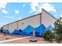 Side view of a large commercial building with a blue mountain mural and a well-maintained gravel landscape at 48295 Shetland Dr, Bennett, CO 80102