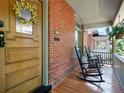 Relaxing front porch with rocking chairs, wood flooring and brick wall creating a welcoming ambiance at 562 N Pennsylvania St, Denver, CO 80203