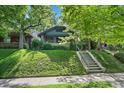 Home exterior on a lush green lot with mature trees and a concrete staircase leading to the entrance at 756 Steele St, Denver, CO 80206