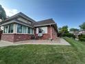 Charming brick home featuring a sunroom, manicured lawn, and mature trees at 9762 Appletree Pl, Thornton, CO 80260