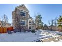 Two-story house with stone and siding exterior, two-car garage, and snowy front yard at 23320 E Berry Ave, Aurora, CO 80016