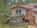 Striking exterior view of a home featuring a deck, large windows, and natural rock features at 7585 Native Dancer Trl, Evergreen, CO 80439