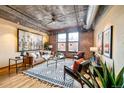 Spacious living room with exposed brick walls, industrial-style ceiling, hardwood floors, and a large window at 1801 Wynkoop St # 411, Denver, CO 80202