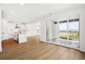 Open-concept living space with wood floors, white kitchen, and sliding doors to outdoor patio at 8213 Butte Creek St, Littleton, CO 80125