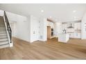 Spacious living area with a modern staircase, light wood floors, and an open view of the kitchen at 8213 Butte Creek St, Littleton, CO 80125