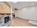Open-concept living room with a stone fireplace, skylight, hardwood floors, and neutral paint at 63 S Sable Blvd # E22, Aurora, CO 80012