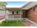 Inviting covered front porch featuring a white railing, brick accents, and manicured landscaping at 1901 S Union Pl, Lakewood, CO 80228