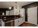 Galley kitchen featuring stainless steel appliances, pendant lighting, black counters and black accent wall at 2430 W 82Nd Pl # 2F, Westminster, CO 80031
