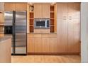 A view of the kitchen featuring a stainless refrigerator, microwave, and natural wood cabinets at 2770 S Elmira St # 2, Denver, CO 80231