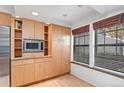 A view of the kitchen featuring a stainless microwave and natural wood cabinets at 2770 S Elmira St # 2, Denver, CO 80231