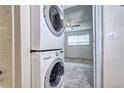 This unit features a convenient, stacked washer and dryer, as well as a view into the carpeted bedroom at 7260 S Gaylord St # E26, Littleton, CO 80122