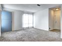 Bright living room features neutral carpet, a large window, and a blue door at 7260 S Gaylord St # E26, Littleton, CO 80122
