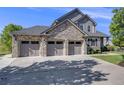 Spacious three-car garage with gray doors, stone accents, and ample parking space on a sunny day at 3041 Starling Ct, Castle Rock, CO 80109