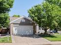 A well kept one-story home with gray siding, stone accents, a two car garage and a beautiful front yard at 8915 W Quarto Pl, Littleton, CO 80128