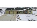 Single-story home with a three-car garage, stone accents, and landscaping in a wintery setting at 39200 E 148Th Ct, Keenesburg, CO 80643