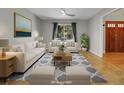 Bright, staged living room with plush furniture, neutral walls, and a large window overlooking the front yard at 12362 E Vassar Dr, Aurora, CO 80014