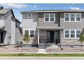 Inviting two-story townhome with stone accents, a covered front porch, and tidy landscaping at 1422 Hudson Pl, Longmont, CO 80501