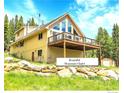 Beautiful mountain chalet with a large deck, surrounded by trees and rocks, offering a perfect retreat at 1176 Raven Ridge Rd, Idaho Springs, CO 80452