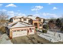 Two-story home with a three-car garage and a snow-covered yard. American flag displayed at 8932 Tuscany Ln, Highlands Ranch, CO 80130