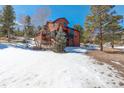 Exterior angle of a home with a wood exterior and deck surrounded by snow and trees at 31299 Manitoba Dr, Evergreen, CO 80439