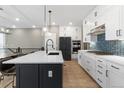 Modern kitchen features white cabinets, black island with quartz countertop, and stainless steel appliances at 17233 W 93Rd Pl, Arvada, CO 80007